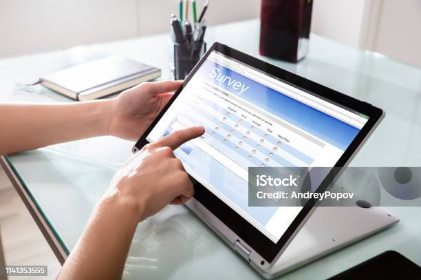 Businessperson Filling Online Survey Form On Digital Laptop Stock Photo - Download Image Now