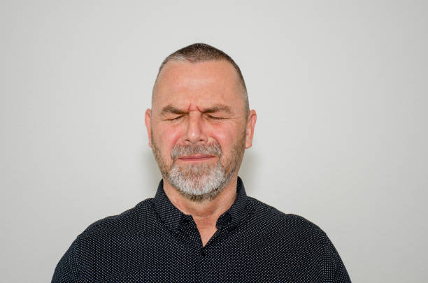 Close up of right eye, cheek and ear of a middle aged (early 50s) white caucasian male.  Person is unshaven, appears stressed, staring at the camera.  Belfast, Northern Ireland.