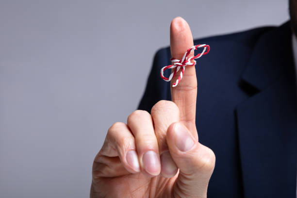 string on person's finger - reminder memories human finger string imagens e fotografias de stock