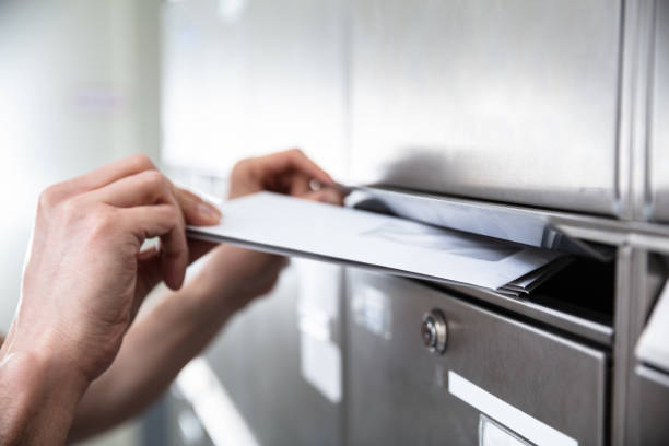 human es hand inserting letters in mailbox - briefkasten stock-fotos und bilder