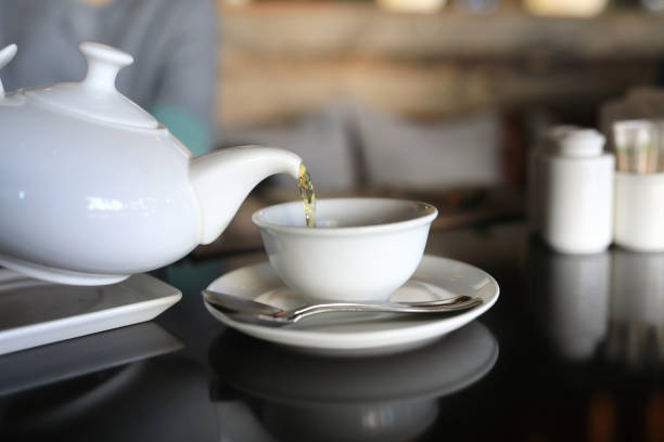 istock Person pours tea from white teapot 1141355904