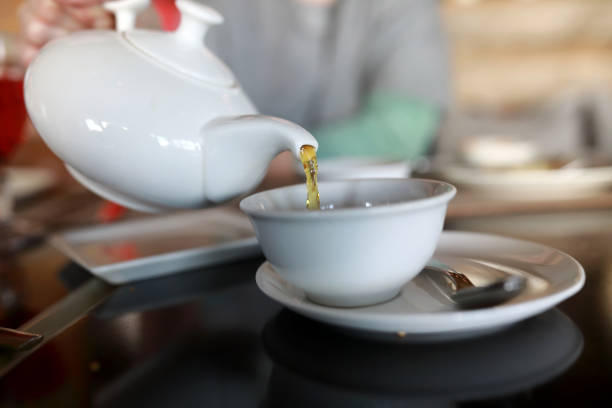 istock Person pouring tea from white teapot 1141355906