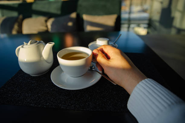 man hand holding cup with tea. kettle on background