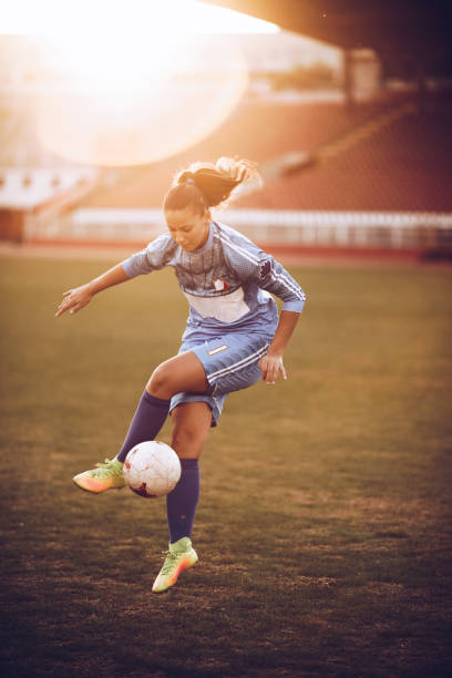 joueur de soccer féminin déterminé pratiquant avec la balle sur le terrain. - soccer skill soccer ball kicking photos et images de collection