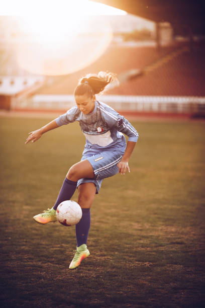 Determined female soccer player practicing with ball on the field. Full length of teenage soccer player kicking the ball on a sports training at stadium. womens soccer stock pictures, royalty-free photos & images