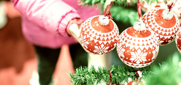 istock Red Christmas Balls on the tree, young girl touching them 1141362822