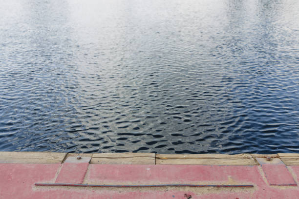 Harbor wall with two black bollards and calm harbor water Empty boat berth