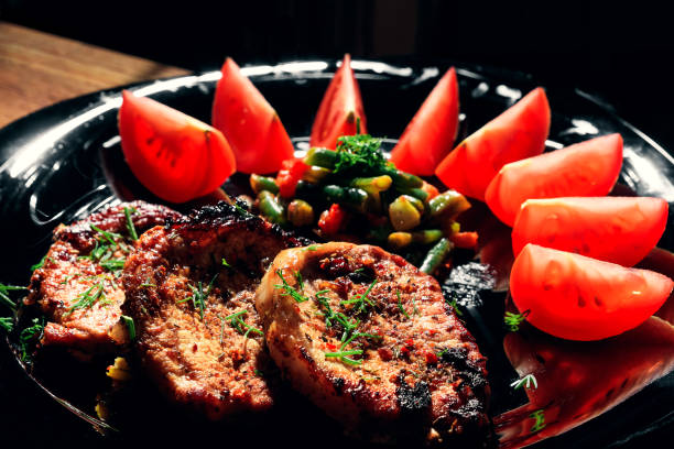 Tasty pork meat grilled  with fries, fresh lettuce, cucumber and tomato on a wooden background. Copy space. View from above.