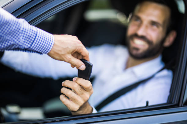 Here is your new car key! Close up of businessman sitting inside of a car and taking new car keys from a sales person. car city urban scene commuter stock pictures, royalty-free photos & images
