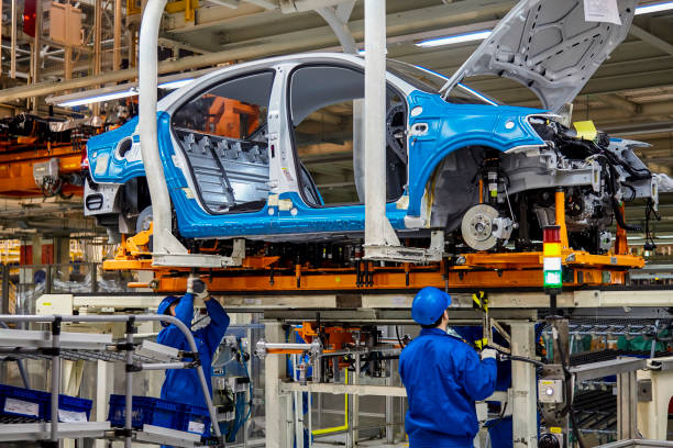 los trabajadores están instalando el firmware del chasis del coche en la línea de producción del taller de manufactura volkswagen de shanghái - chinese production fotografías e imágenes de stock