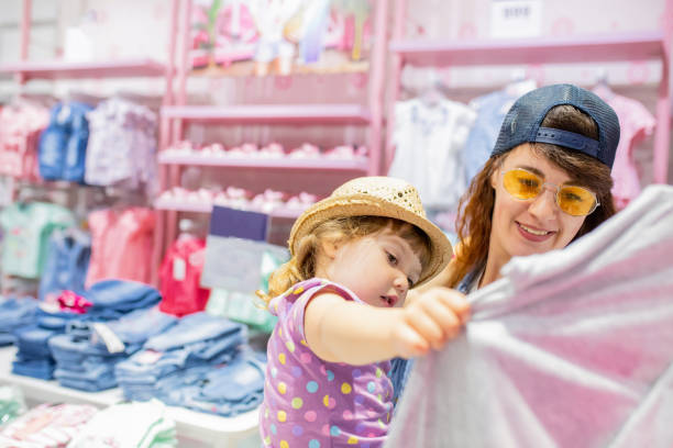 mother and her cute little daughter having fun together at the clothes store - boutique shopping retail mother imagens e fotografias de stock