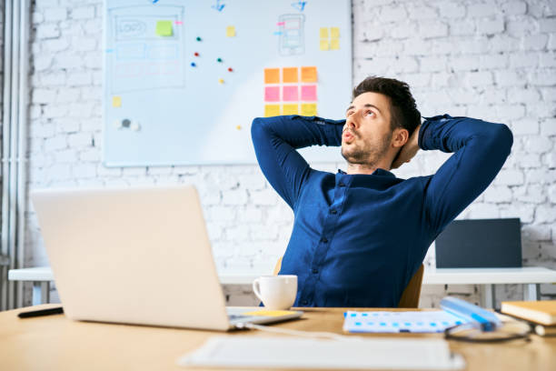 disfrutando de un descanso del trabajo. empresario sentado con las manos detrás de la cabeza, bebiendo café y silbando - silbar fotografías e imágenes de stock