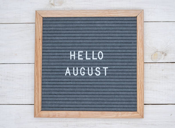 texto en inglés hello august en un tablero de cartas en letras blancas sobre un fondo gris - bienvenido agosto fotografías e imágenes de stock