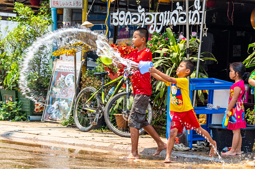 Vang Vieng, Laos - April 14, 2018: Kids throwing water on the streets of Vang Vieng during the Lao New Year celebrations