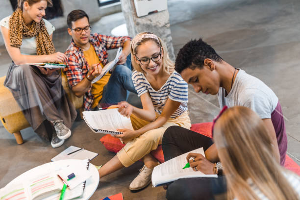 istock Group of happy students cooperating while reading lectures from textbooks. 1141388924