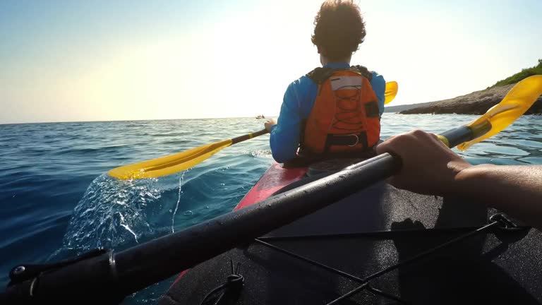 POV Person paddling in a tandem sea kayak on a sunny day