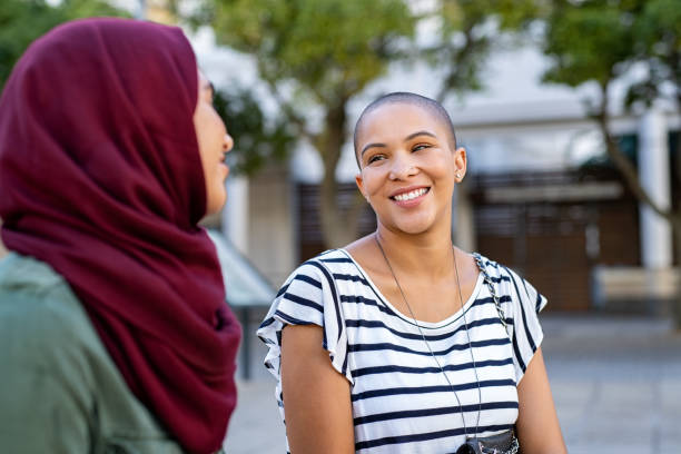 Muslim woman with friend Cheerful african american woman in conversation with muslim girl. Happy multiethnic friends in street looking at each other while in a conversation. Beautiful woman with friend in hijab talking to each others. version 2 stock pictures, royalty-free photos & images