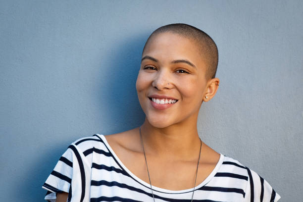 Happy stylish bald woman Closeup portrait of beautiful stylish woman on lightblue background. Smiling bald girl looking at camera isolated against blue background with copy space. Cheerful and satisfied young woman with shaved head in casual. huge black woman pictures stock pictures, royalty-free photos & images