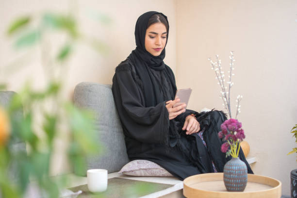 Beautiful middle eastern woman using smart phone while resting on balcony