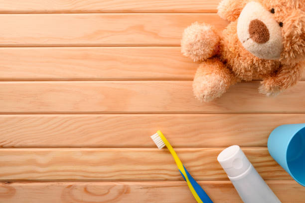 Children's oral hygiene with cleaning elements on wooden table and stuffed toy. Horizontal composition. Top view