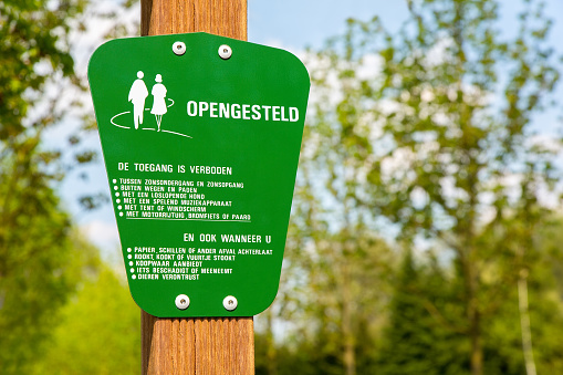 Green traffic sign for behaviour of dutch walkers in forest. When you want to hike in nature here, you have to behave: no music, no unleashed dogs, stay on the path, not disturb animals, no windshield, no waste, no tent, no motor, no moped, no horse, no fire, no damage.