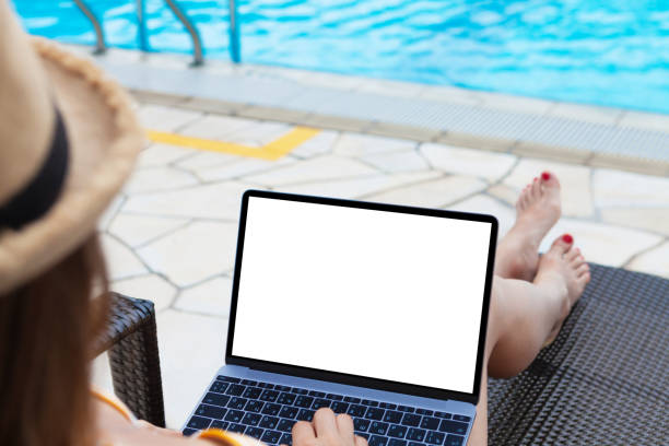 istock Young woman using laptop near a swimming pool 1141398556