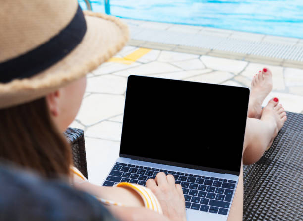 istock Young woman using laptop near a swimming pool 1141398577