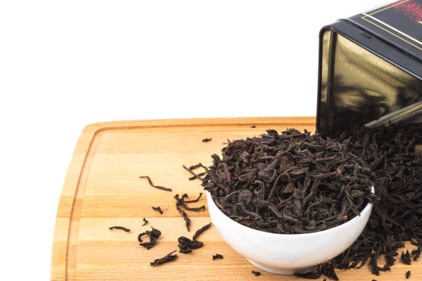 istock Dried tea is poured into a ceramic cup on a wooden board on a white background. 1141399635