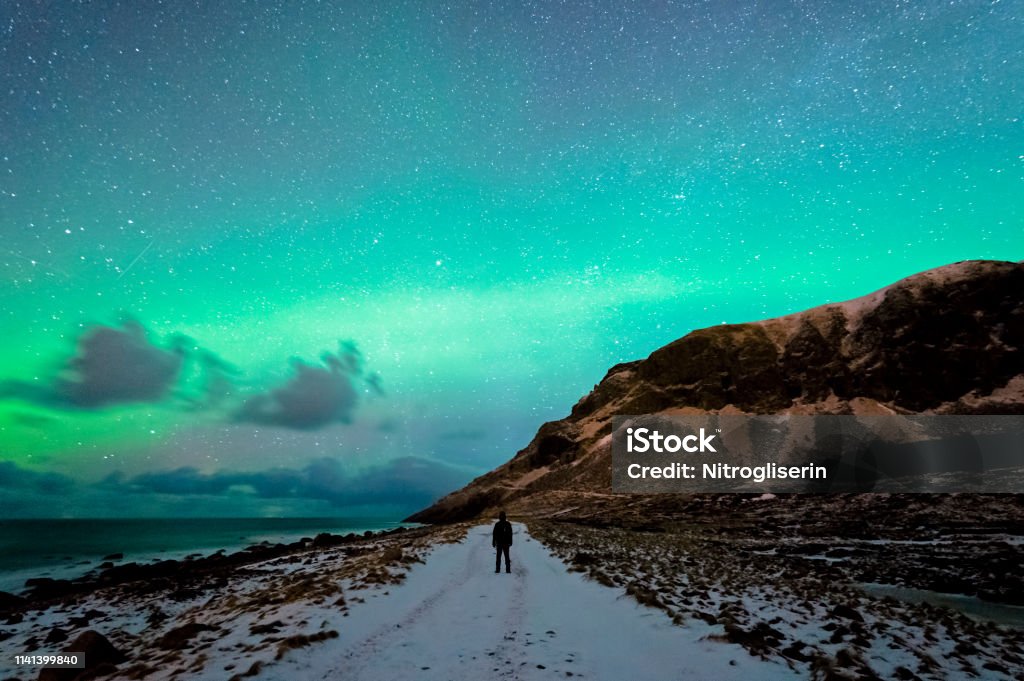 Enjoying the Northern Lights in Unstad Enjoying the sky with Northern lights spotted in Unstad, Lofted in a cloudy sky. Aurora Borealis Stock Photo