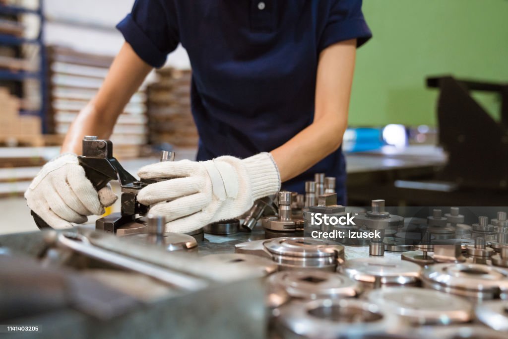 Female trainee using manufacturing machinery Midsection of female apprentice using manufacturing machinery. Engineer is working in factory. She is in blue t-shirt. 30-34 Years Stock Photo