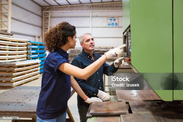 Instructor Discussing With Trainee In Factory Stock Photo - Download Image Now - Guidance, 30-34 Years, 55-59 Years