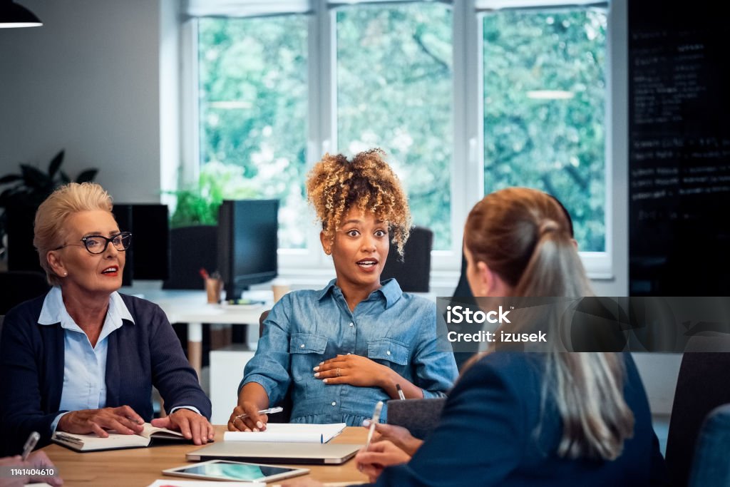 Shocked pregnant businesswoman looking at coworker Shocked pregnant businesswoman looking at colleague. Female expertise are planning new strategies. They are sharing ideas at desk in office. Shock Stock Photo
