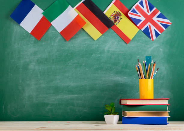 backpack, flags of Spain, France, Great Britain and other countries, books and school supplies of the blackboard Learning languages concept - flags of Spain, France, Great Britain and other countries, books and chancellery on the background of the blackboard german language photos stock pictures, royalty-free photos & images