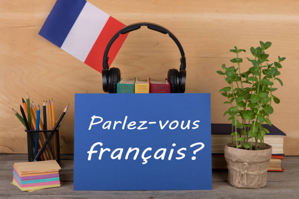 フランス語を学ぶ概念 - テキスト付きの紙 "parlez-vousフランセ?(パルレス・ヴー・フランセ?)、フランスの旗、本、ヘッドフォン、木製の背景に鉛筆 - text talking translation learning ストックフォトと画像