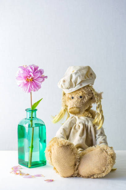 istock cute teddy bear with vase and flower 1141406303