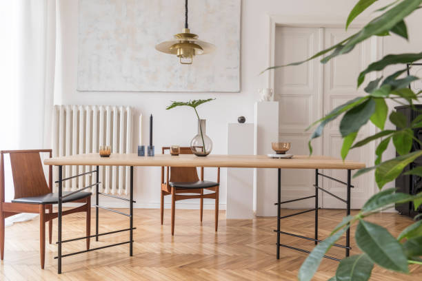 istock Eclectic and elegant dining room interior with design sharing table, chairs, gold pendant lamp, abstract paintings, piano and stylish accessories. Minimalistic decor. Brown wooden parquet. Real photo. 1141409301