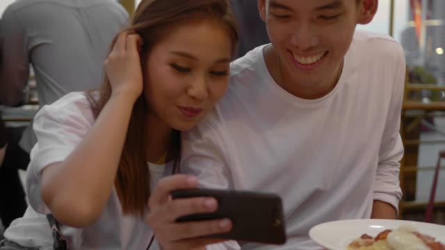 Cute Asian Couple in a Cafe with Smartphone