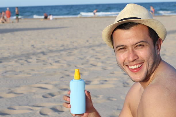 istock Young man holding suntan lotion bottle 1141409915