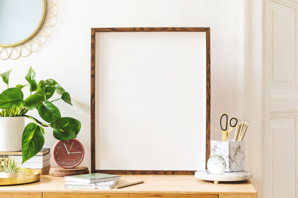 istock Modern scanidnavian interior with mock up photo frame, design office accessories and plants on the wooden desk. Beautiful mirror on the white wall. Creative desk of home decor. Warm and sunny room. 1141409957