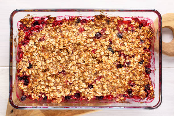 istock Apple and berry crumble, topped with oats in glass baking dish on white table. Crispy fruit pie, healthy summer dessert. Top view, close-up. 1141410890