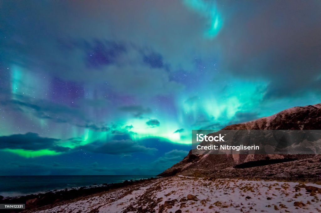 Northern Lights in Unstad Northern lights spotted in Unstad, Lofted in a cloudy sky. Arctic Stock Photo