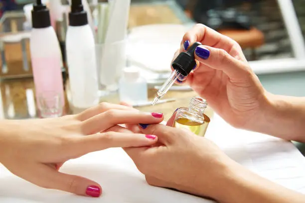 Nails top coat finishing vernis after nail polish in woman hands at salon