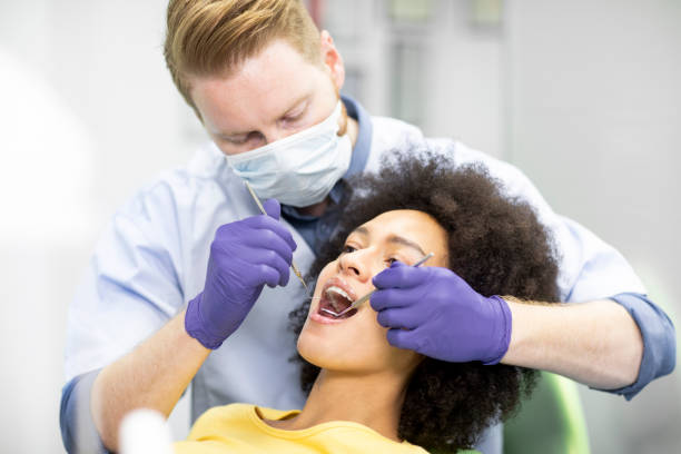 istock Dentist using an excavator sickle probe and a mouth mirror to perform a dental check-up 1141415560