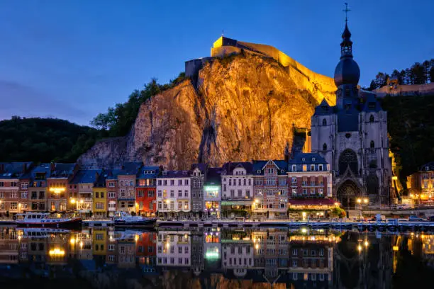 Night view of Dinant town, Collegiate Church of Notre Dame de Dinant over River Meuse and Pont Charles de Gaulle bridge and Dinant Citadel illuminated in the evening. Dinant,  Belgium