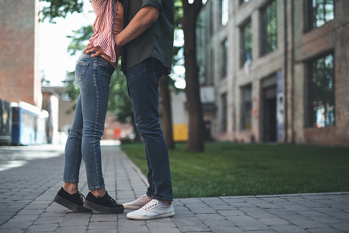 Sweet touch. Young girl wearing casual clothes and standing on the toes while her beloved man putting hands on her waist during their date