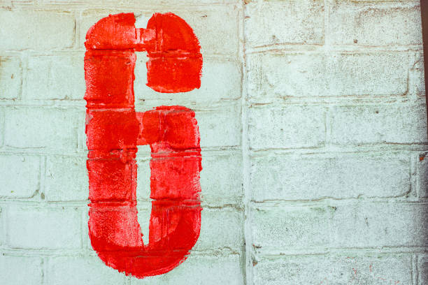 istock Number Six Drawn By Red paint On Whitewashed Brick Wall. Shabby Building With Damaged cracked Plaster 1141417468