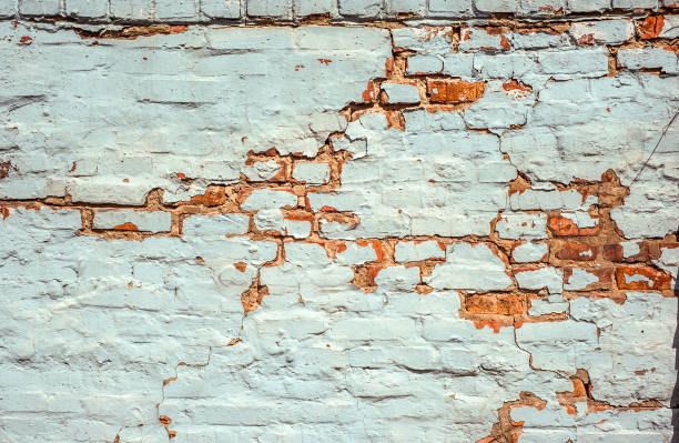 istock Old Brick Wall White Painted Texture. Shabby Building With Damaged cracked Plaster 1141417496