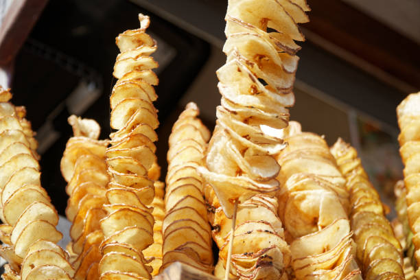 Fried potato chips on stick, Spiral potatoes fried, on wooden sticks, spiral. Selling food at the market. Unhealthy fried street food. Fried potato chips on stick, Spiral potatoes fried, on wooden sticks, spiral. Selling food at the market. Unhealthy fried street food elefant stock pictures, royalty-free photos & images