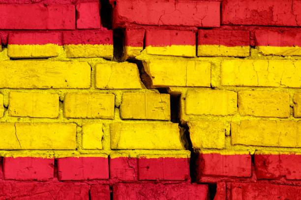 Flag of Spain on the brick wall with big crack in the middle. Destruction and separatism concept stock photo