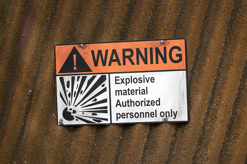 Warning sign on a corrugated iron wall with the inscription: explosive material authorized personnel only